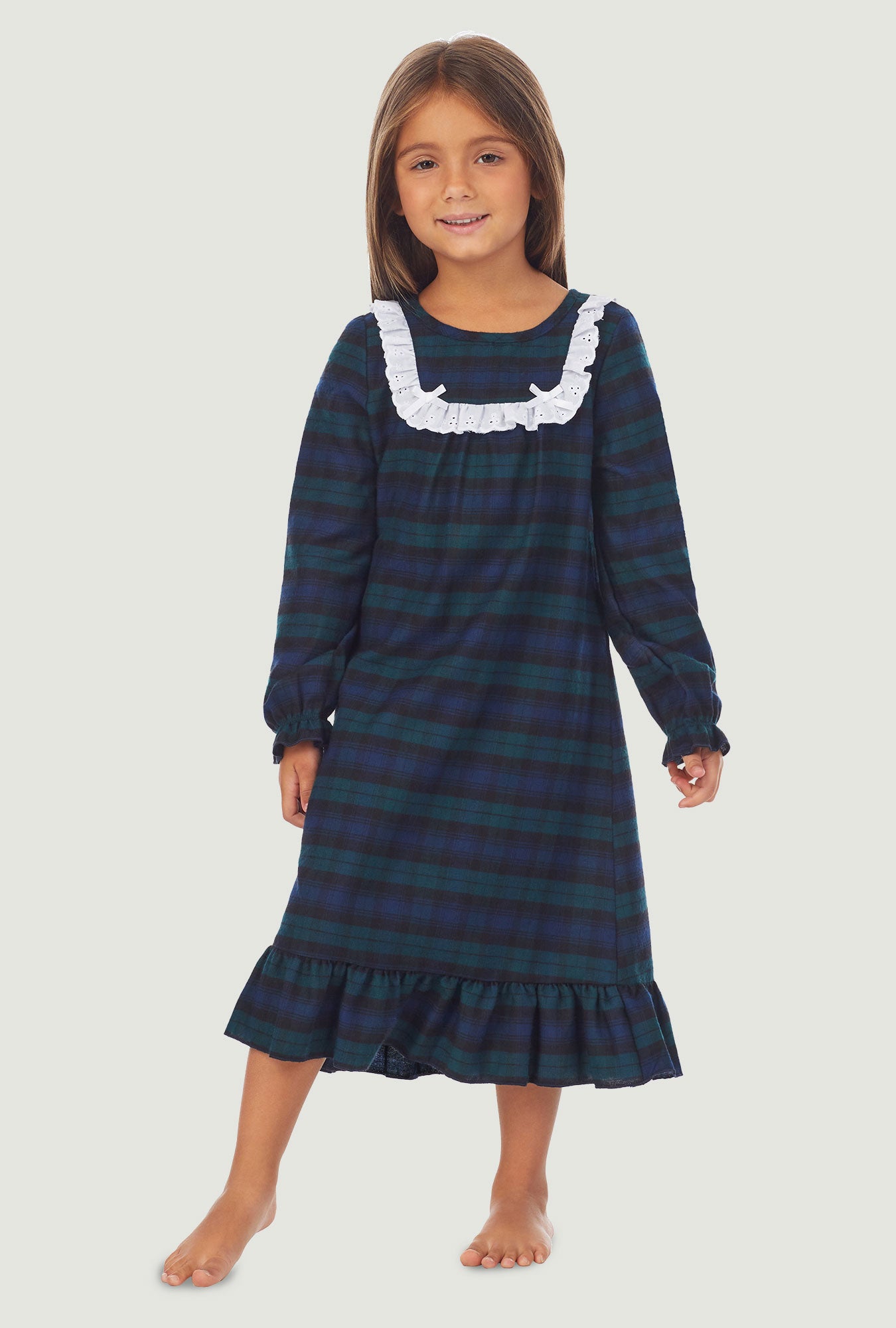 A girl wearing a black watch plaid long sleeve nightgown.