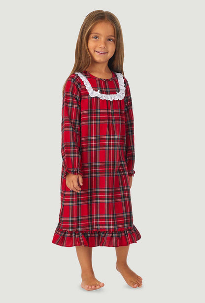 A girl wearing a red tartan long sleeve nightgown.